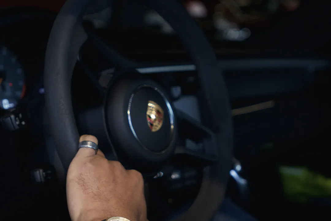 A driver’s hand on a Porsche steering wheel, shot for T.A Auto in Sandnes
